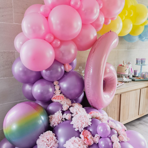 belle arche de ballons organiques pastel avec des ballons nacrés en rose clair, jaune, bleu clair et parme.